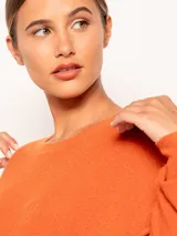 Sweater tejido color naranja de manga larga y cuello redondo, con detalles de tajo en los laterales.