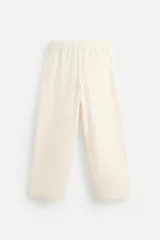 Pantalón color crema de corte amplio, con cintura elástica ajustable con cordón, bolsillos laterales y trasero, cierre frontal con cremallera y botón.