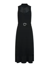 Vestido midi tejido negro con cuello alto, sin mangas, calado y falda con volantes. Incluye cinturón con hebilla irregular.