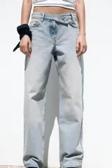 Pantalón de jean celeste de tiro alto, corte recto y largo hasta el tobillo. Tiene cinco bolsillos, efecto lavado y cierre frontal con cremallera y botón metálico cruzado.