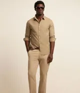 Pantalón de vestir color marrón, de corte recto, con bolsillos laterales y traseros. Se ajusta a la cintura con cinturón de cuero marrón.