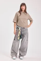 Pantalón de jean gris de corte ancho con bolsillos laterales y pañuelo estampado atado a la cintura.