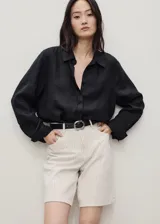 Shorts de tiro alto color crema con finas rayas verticales, trabillas para cinturón, cierre frontal con cremallera y botón, y cinco bolsillos.