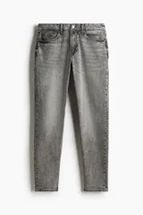 Pantalón de jean gris con efecto lavado, corte regular tapered, tiro medio, cinco bolsillos y cierre con botón y cremallera.