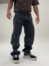 Pantalón de jean negro con efecto lavado, corte amplio tipo baggy y costuras verticales en el frente.