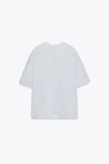 Camiseta gris jaspeado de corte amplio, cuello redondo y mangas cortas. Estampado frontal con la frase "Los Angeles 8500 Beverly Blvd, Los Angeles, CA 90048" en color azul.