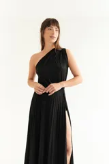 Vestido largo negro de lurex con un solo hombro y falda plisada con abertura lateral.