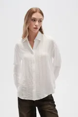 Camisa blanca de viscosa con cuello clásico, cierre frontal con botones y mangas largas. Presenta un sutil diseño de líneas verticales con strass. Corte al cuerpo.