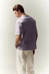 Remera lila de algodón pesado, corte holgado, con cuello redondo ribeteado y hombros caídos.