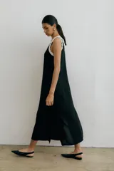 Vestido midi negro con escote en V, breteles finos con volados blancos y tajos laterales.