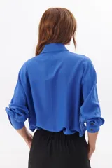 Camisa color azul de corte suelto, con detalles en las mangas y cuello clásico.