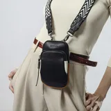 Cartera phone bag negra con bolsillo frontal y correa gruesa de galón regulable y desmontable con diseño de espiga en blanco y negro.