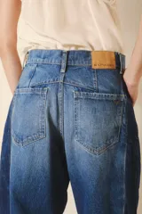 Pantalón jean de tiro alto, corte amplio y pierna ancha con parches en diferentes tonos de azul.