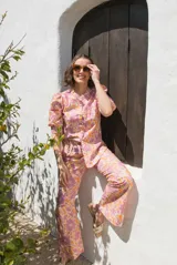 Camisa de lino estampada con flores en tonos rosa y naranja, con cuello mao, mangas cortas abullonadas y cierre frontal con botones.