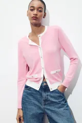 Chaqueta celeste de punto con cuello redondo y manga larga. Tiene cierre frontal con botones y detalle de falsos bolsillos delanteros con ribete blanco.