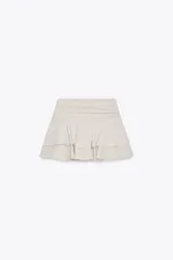 Falda pantalón color crema, de tiro medio, con volantes en capas y cierre lateral con cremallera.