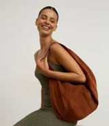 Bolso hobo de gamuza color marrón, con forma de media luna, cierre de cremallera y bretel ancho.