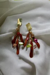 Aros colgantes con base triangular color crema y dijes colgantes de bronce esmaltado en forma de hojas y círculos de colores.