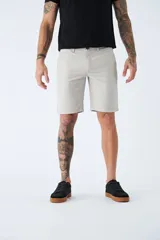 Bermuda color beige de corte chino, con bolsillos laterales, cierre con cremallera y botón, presillas para cinturón y logo bordado. Confeccionada en lino y algodón.