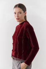 Polera de color burdeos, de manga larga y con diseño de líneas plateadas.