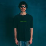 Remera oversize negra con efecto lavado y estampado frontal con el texto "KABOA INDUSTRIES SABOR 100% URUGUAYO" en color verde.