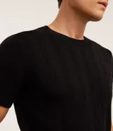 Remera negra de algodón con textura trenzada, cuello redondo y mangas cortas.