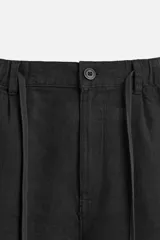 Bermuda negra regular fit confeccionada en tejido con mezcla de algodón y lino. Cintura elástica ajustable con cordón. Pliegues frontales. Bolsillos laterales y traseros de vivo. Cierre frontal con cremallera y botón.