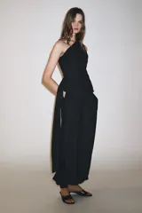 Pantalón de tiro medio confeccionado en hilatura con mezcla de viscosa, color negro. Presenta bolsillos laterales ocultos en costura, bajo acabado en puño con botones y cierre frontal con cremallera, botón y ganchos metálicos.