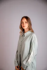 Camisa celeste de corte clásico, con botones frontales y bordados florales en las mangas.