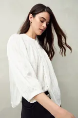 Camisa celeste a rayas verticales, de corte amplio, cuello mao y mangas 3/4 abullonadas.