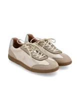 Zapatillas acordonadas de cuero color beige con suela de goma color caramelo y detalle plateado en el talón.