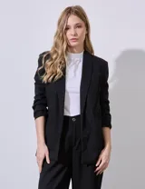 Blazer negro de lino marca Dictionary, con cuello con solapa, bolsillos sastre delanteros, mangas largas fruncidas y forro interno a tono.