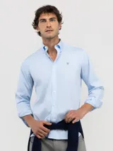 Camisa celeste a rayas verticales, de corte regular fit, cuello button-down, manga larga con puños abotonados y logo bordado en el pecho.