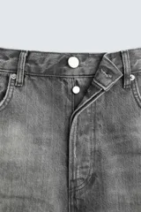 Pantalón de jean gris de corte flare, con cinco bolsillos, lavado con efecto de contraste en las piernas y bajo con acabado irregular.