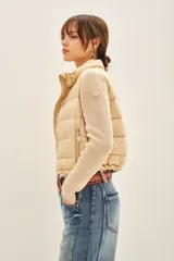 Campera color beige con mangas tejidas, cuello alto y cierre frontal.