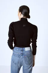 Polera roja de tejido de punto con cuello alto y mangas largas abullonadas en los hombros.