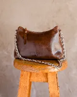 Cartera tipo baguette de cuero color rojo brillante, con correa de cadena plateada.