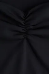 Top negro corto sin mangas en punto suave. Modelo de ajuste ceñido con escote corazón profundo y costura fruncida en el centro del busto.