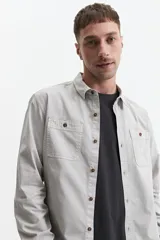 Camisa de manga larga gris oscuro, corte slim, con cartera abotonada, dos bolsillos frontales con botón y confeccionada en 100% algodón.