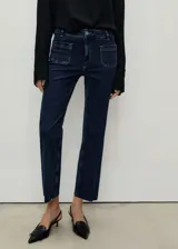 Pantalón de jean azul oscuro, tiro medio, corte recto, con bolsillos delanteros de parche y ruedo desflecado.