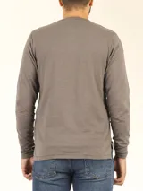 Remera manga larga gris con cuello abotonado y bolsillo azul en el pecho.
