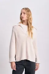 Buzo de punto color crudo con cuello polo y aberturas laterales.