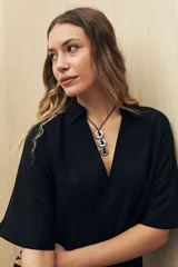 Vestido corto negro de línea relajada con cuello tipo solapa y escote en V profundo, mangas cortas amplias y calce suelto.