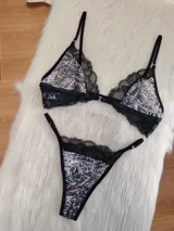 Conjunto de lencería compuesto por un corpiño triangular sin aro con estampado animal print y detalles de encaje negro, y una bombacha tipo colaless con el mismo estampado y borde de encaje negro. El corpiño tiene cierre frontal.