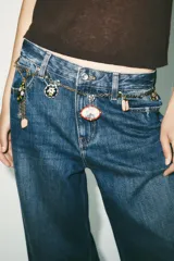 Cinturón tipo cordón con eslabones metálicos dorados y colgantes de charms con piezas de resina de colores. Cierre con mosquetón.