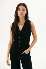 Chaleco negro de tejido de punto con escote en V y cierre frontal con botones.