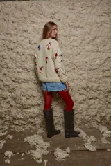 Sweater de lana color crema, tejido a mano con cuello redondo y mangas largas con trenzas. Presenta bordados de figuras esquiando.