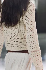 Top color crudo de tejido crochet calado, con cuello redondo y mangas largas acampanadas.