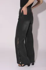 Pantalón de jean gris oscuro con lavado gastado, corte acampanado y tachas plateadas en los laterales.