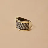 Anillo ancho de plata con diseño trenzado y bordes de oro.
